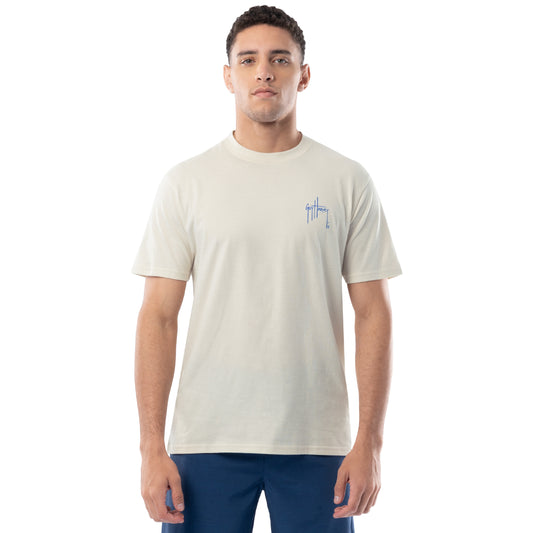 Man wearing a beige t-shirt with a small logo on a white background