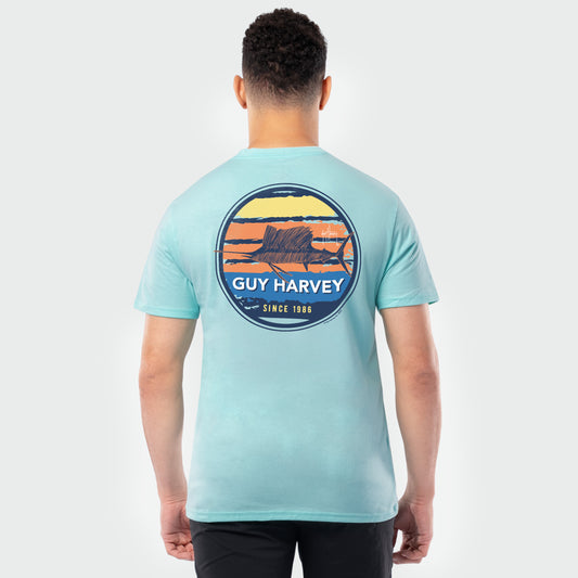 Person wearing a light green Guy Harvey t-shirt with a sailfish graphic on the back against a white background