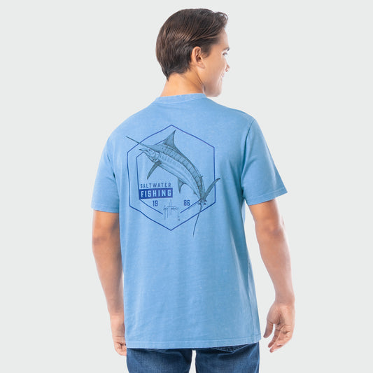 Person wearing a blue washed t-shirt with a marlin graphic on the back against a light gray background