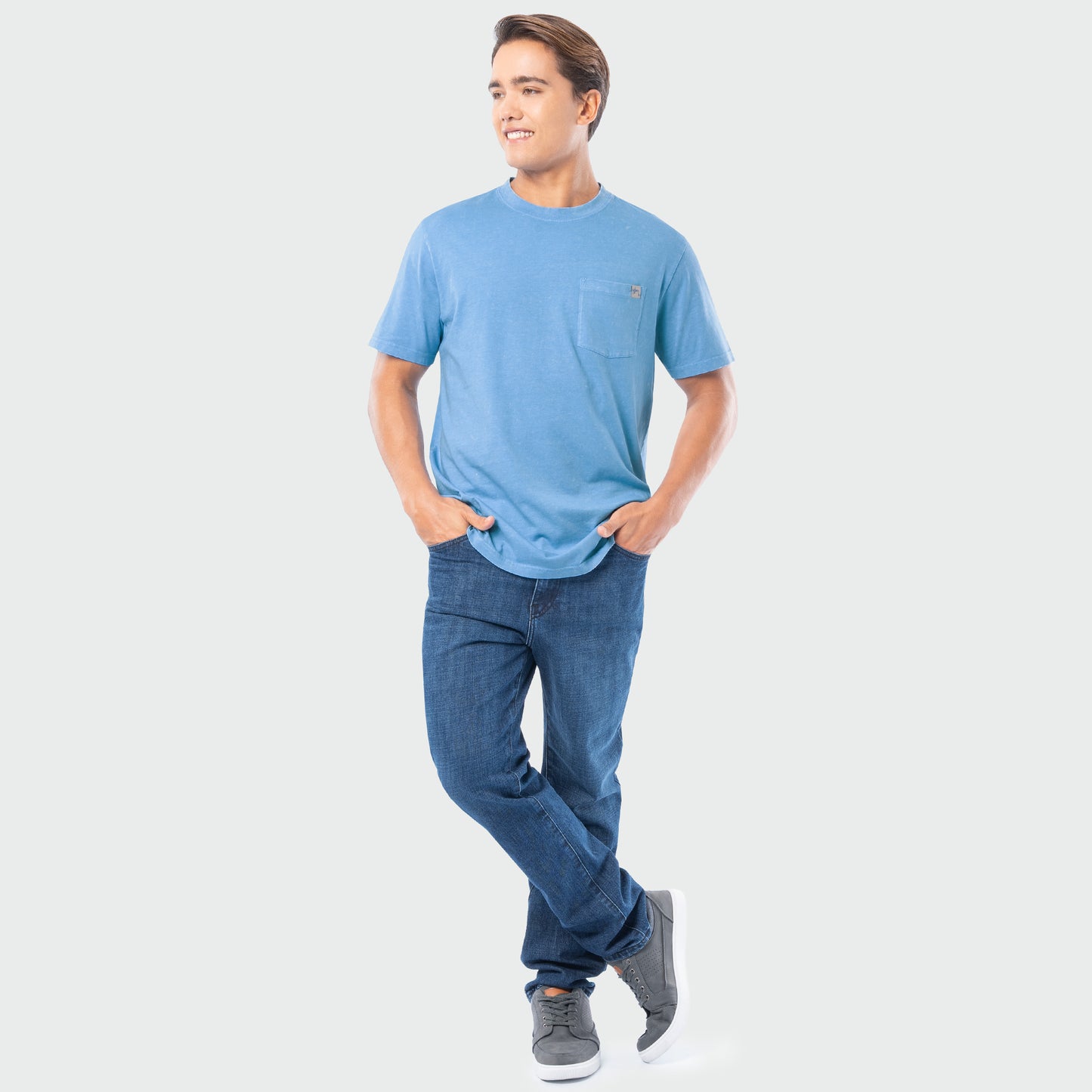 Man wearing a blue t-shirt and jeans on a white background