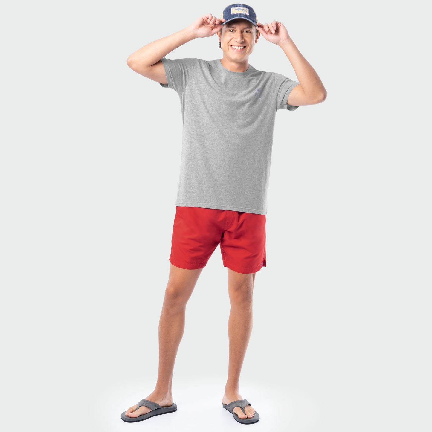 Man wearing a gray t-shirt, red shorts, and a cap on a white background