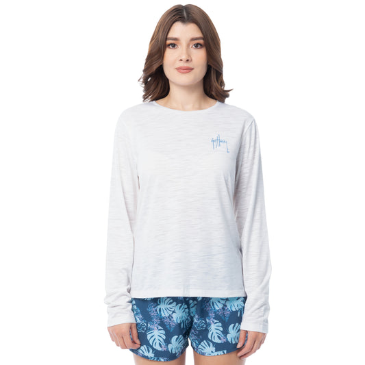 Woman wearing a white long-sleeve shirt and blue floral shorts on a white background