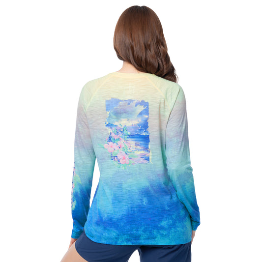 Woman wearing a colorful tie-dye long-sleeve shirt with a floral design on the back, on a white background.
