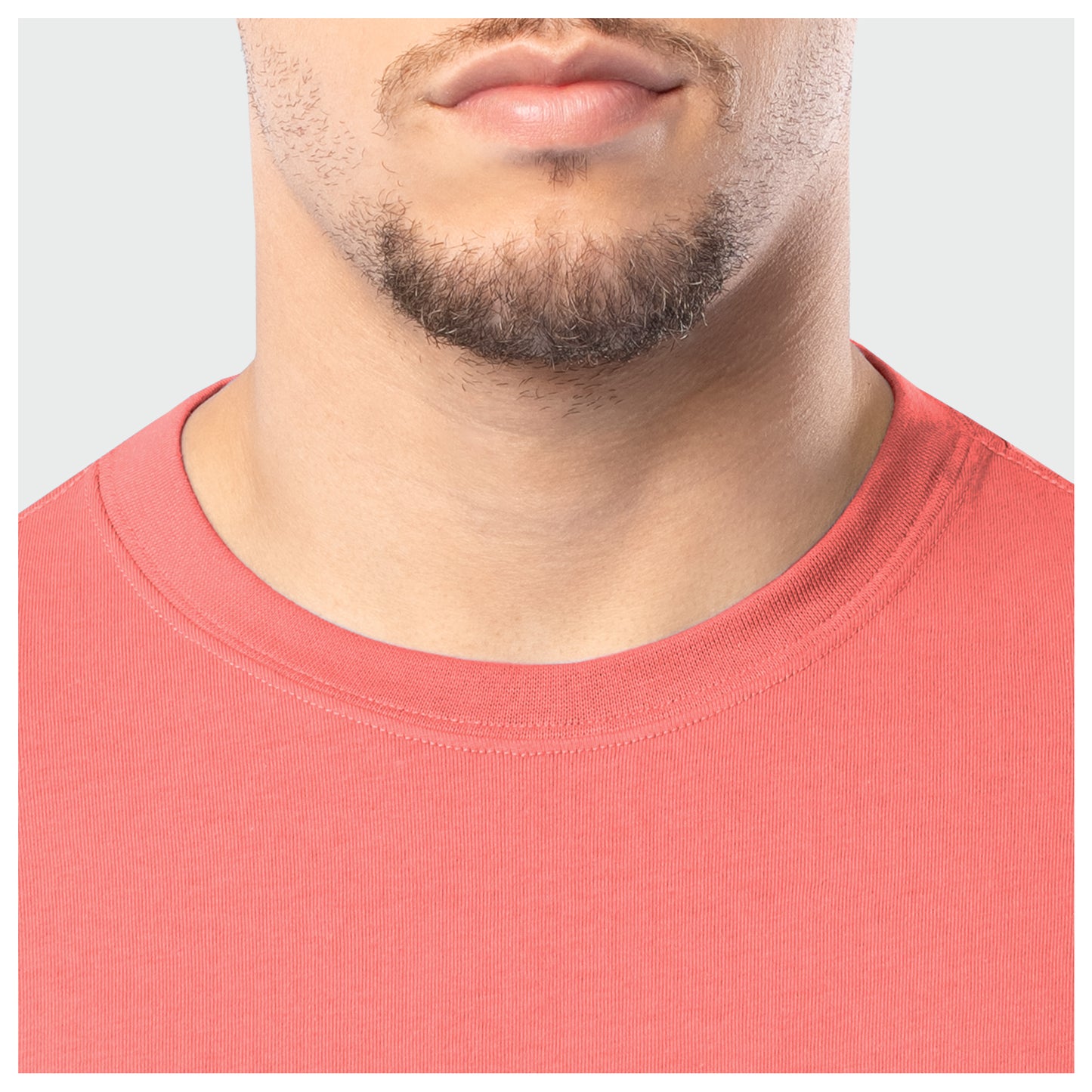 Close-up of a person wearing a coral shirt with a plain background
