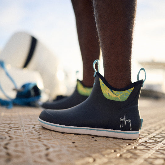 A person wearing Guy Harvey deck boots on a dock. This image takes you to the deck boots collection from Guy Harvey.