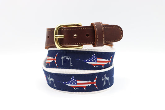 Guy Harvey Men’s USA Marlin Leather Tab Belt with navy cotton webbing, American flag marlin design, brown leather tabs, and brass buckle.