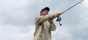A man wearing a Navigator Fleece pullover hoodie from Guy Harvey with a camo pattern while fishing.