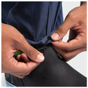 Close-up of a person's hands adjusting the hem of a navy blue fishing pants, pulling a black elastic or hook-and-loop closure tab.