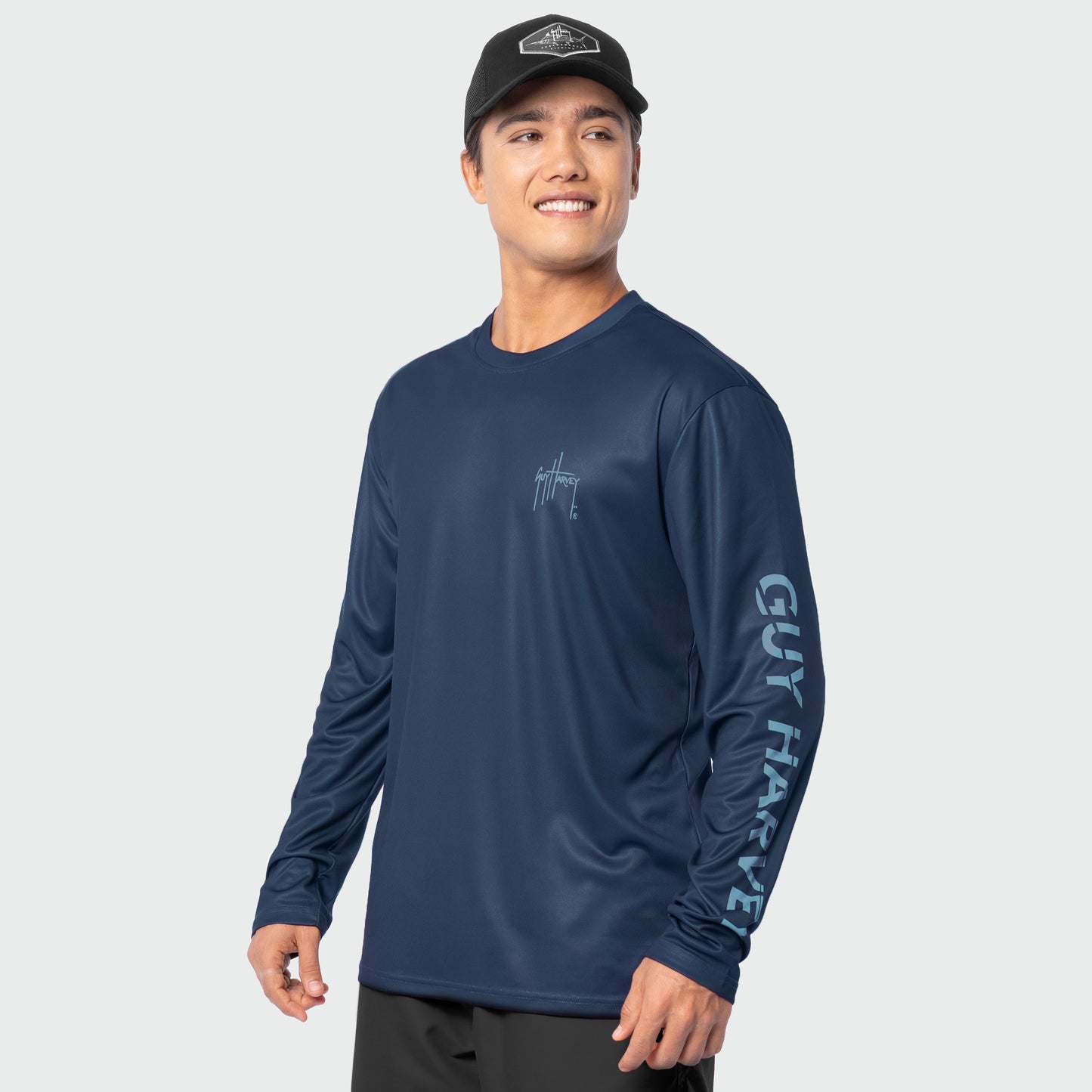 Man wearing a navy long-sleeve shirt with branding on a light gray background