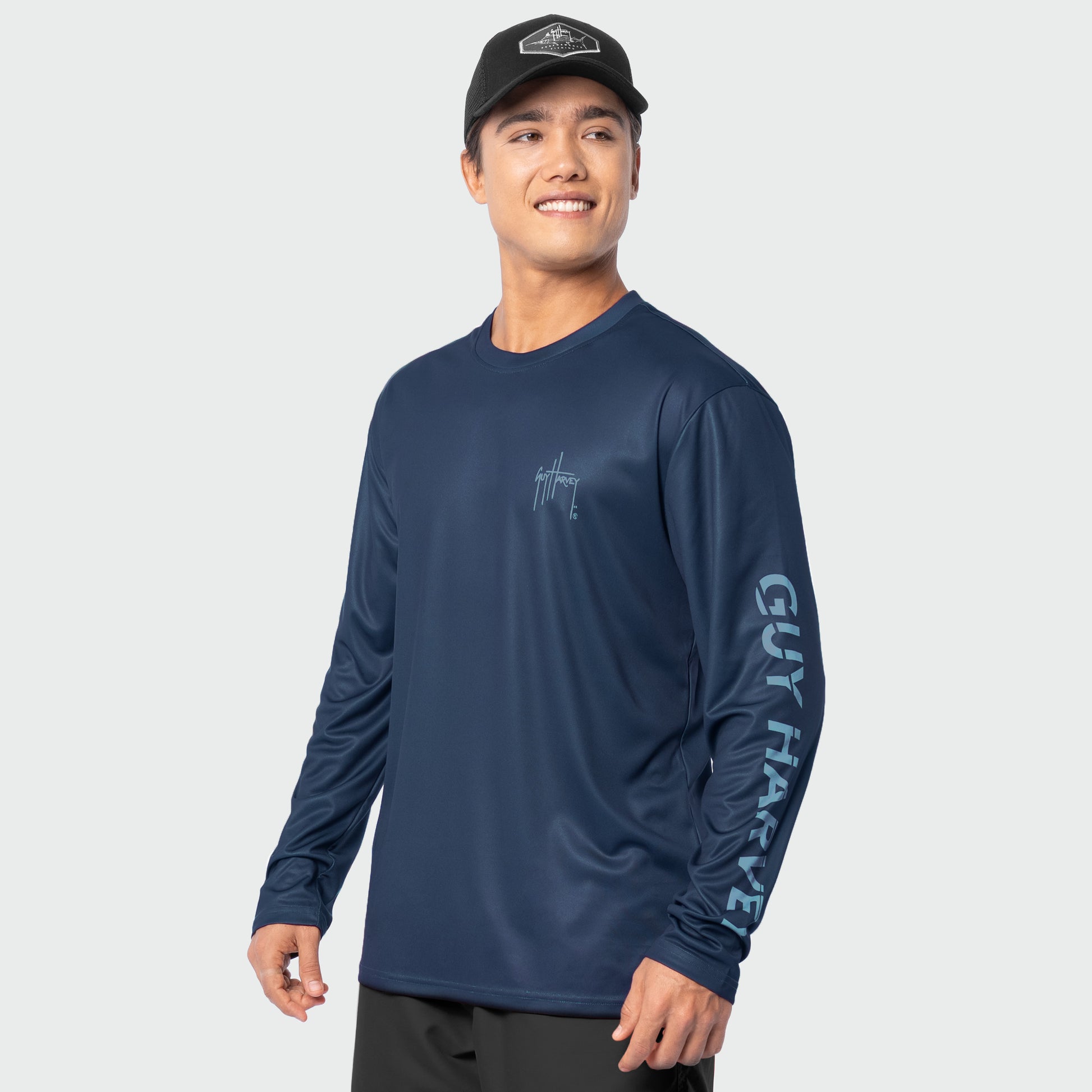 Man wearing a navy long-sleeve shirt with branding on a light gray background