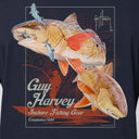 A close-up of a navy blue t-shirt featuring a large graphic print of two redfish with orange and blue accents, along with the text 'Guy Harvey Inshore Fishing Gear' and 'Established 1969'.
