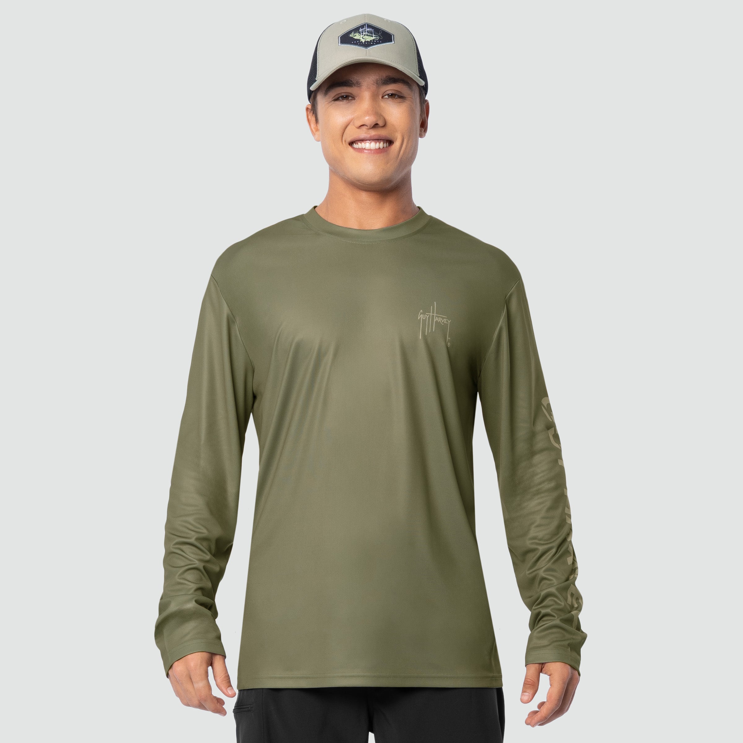 Man wearing an olive green long-sleeve shirt and cap on a light gray background