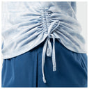 Close-up of a light blue ruched scrub top tied at the waist, paired with navy blue scrub pants.