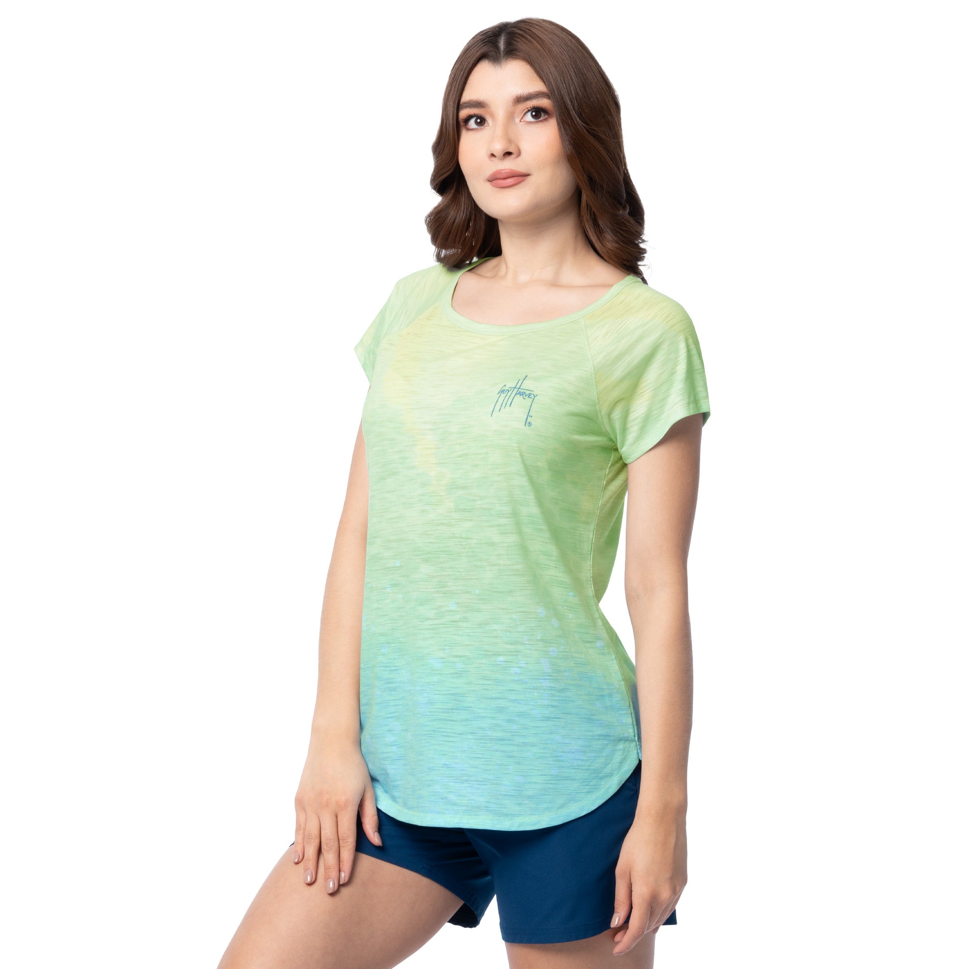 Sideview Woman wearing a green and blue gradient t-shirt with a small Guy Harvey logo on a white background