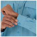 Close-up of a person wearing a light blue shirt with a logo on the sleeve, adjusting the cuff.