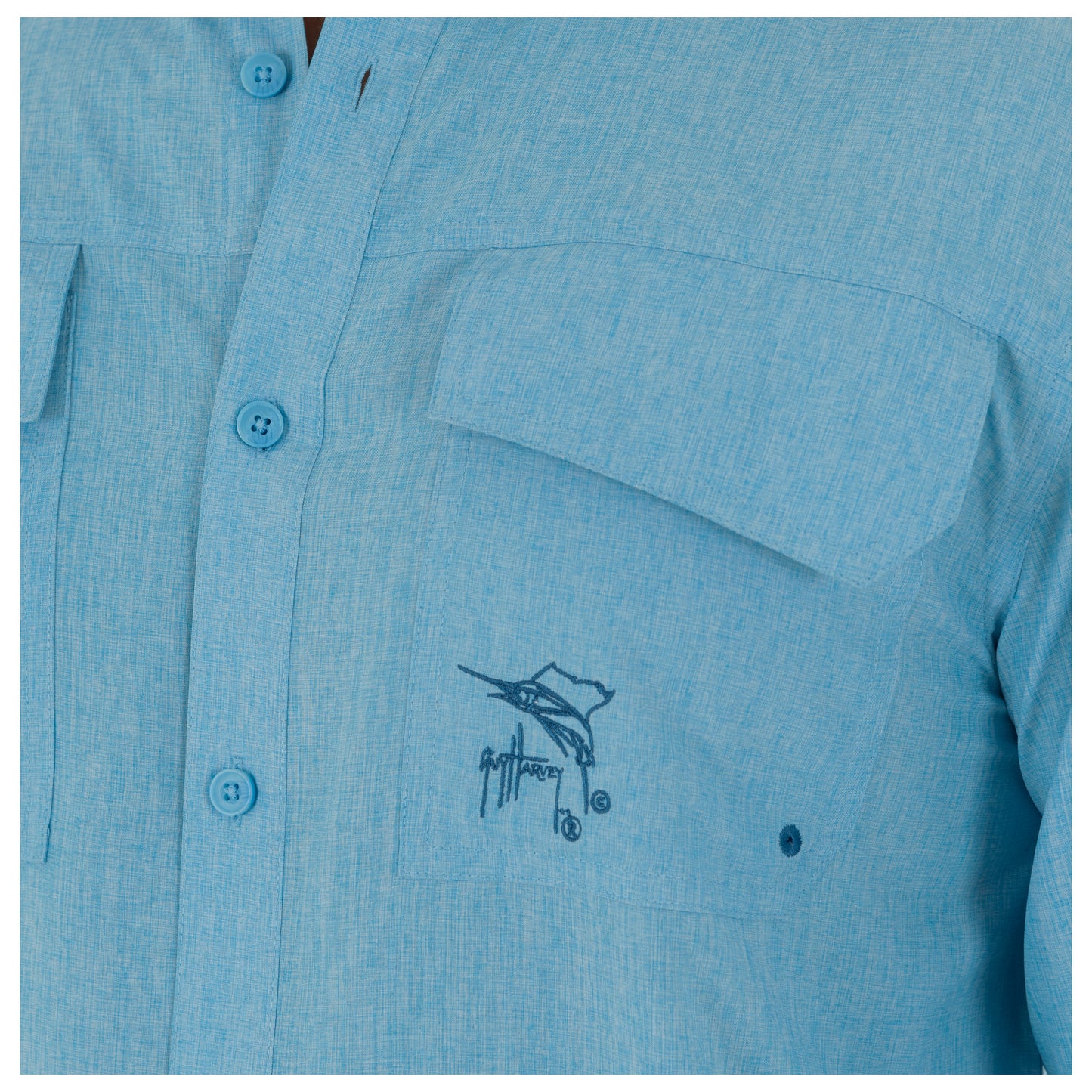 Close-up of a blue shirt with a logo on the chest pocket.