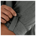 Close-up of a person adjusting the cuff of a gray shirt.