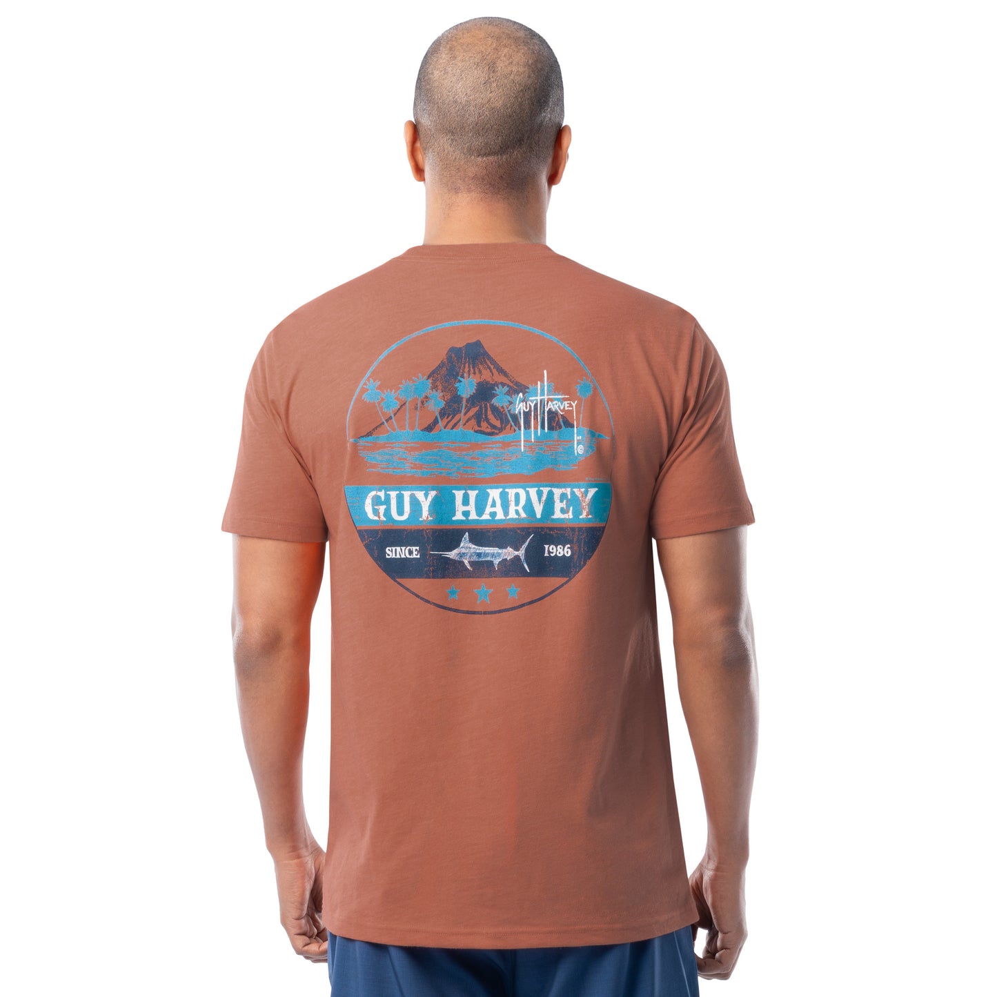 Man wearing a Guy Harvey t-shirt with a volcano graphic design on the back.
