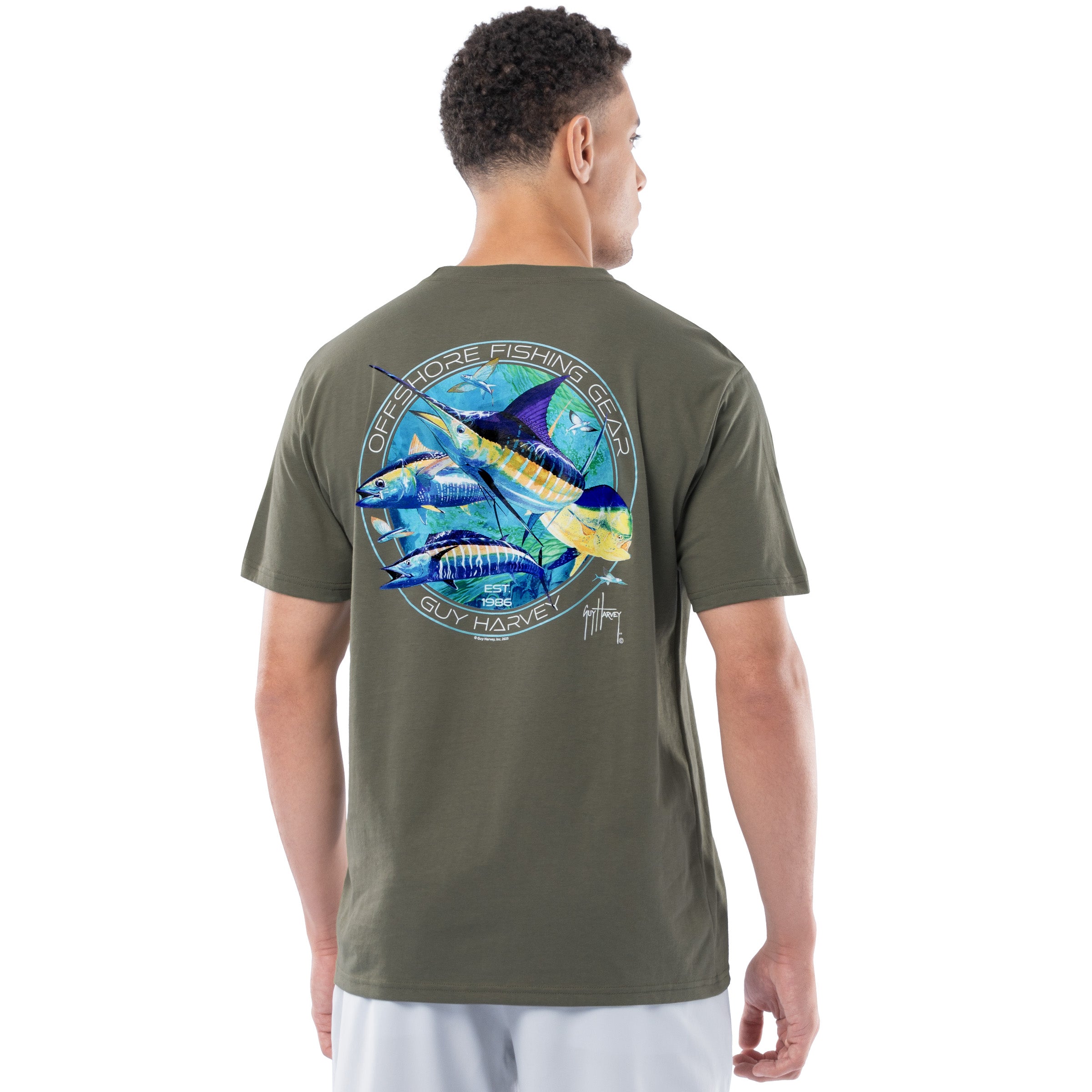 Man wearing a green t-shirt with a colorful Guy Harvey graphic on the back with a marlin, dorado, wahoo and a tuna, on a white background
