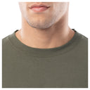 Close-up of a person wearing an olive green t-shirt on a white background