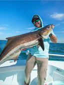 A man smiling holding a huge fish on a boat