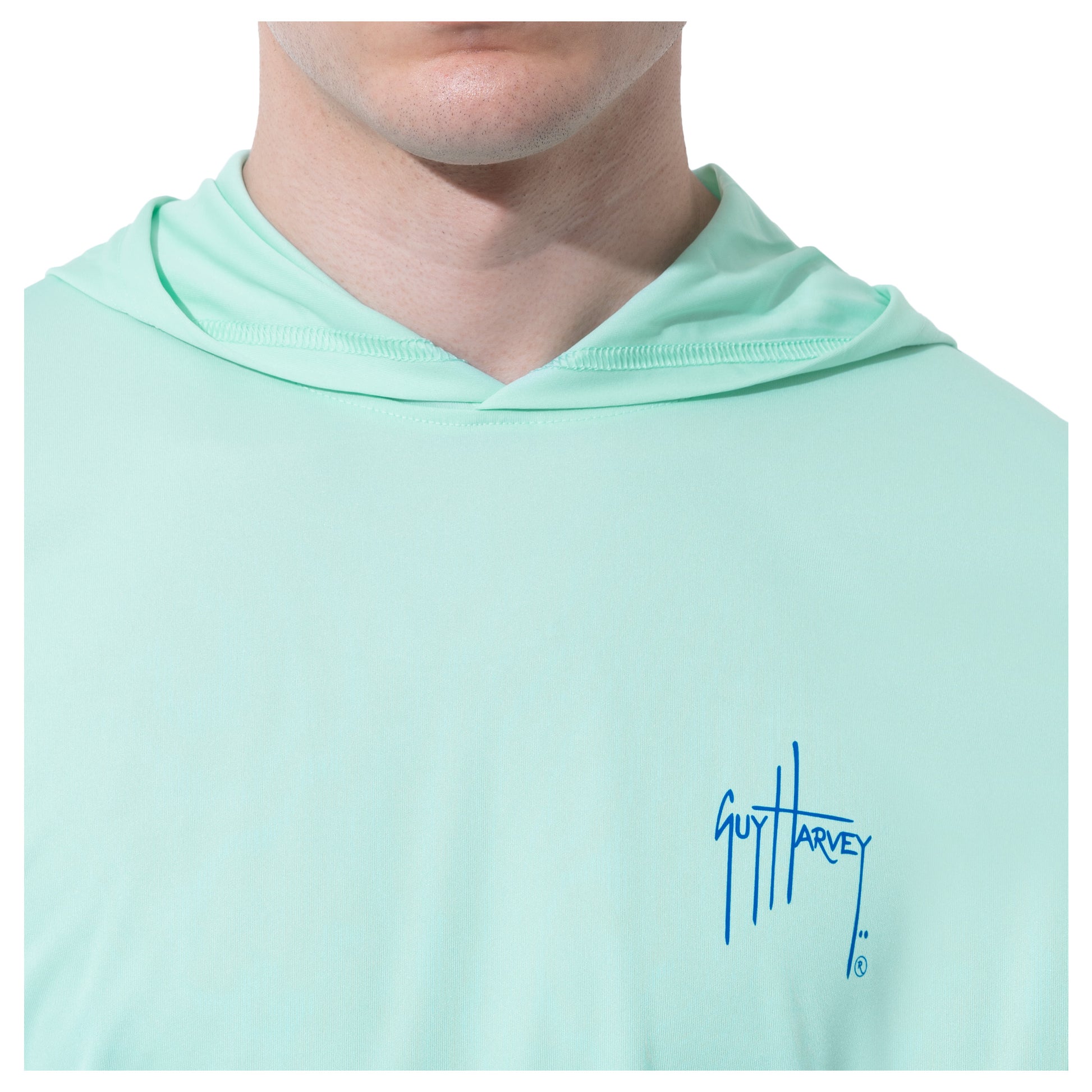 Close-up on the left chest of the men's performance fishing hoodie in beach glass green showcasing the logo with Guy Harvey iconic signature. 