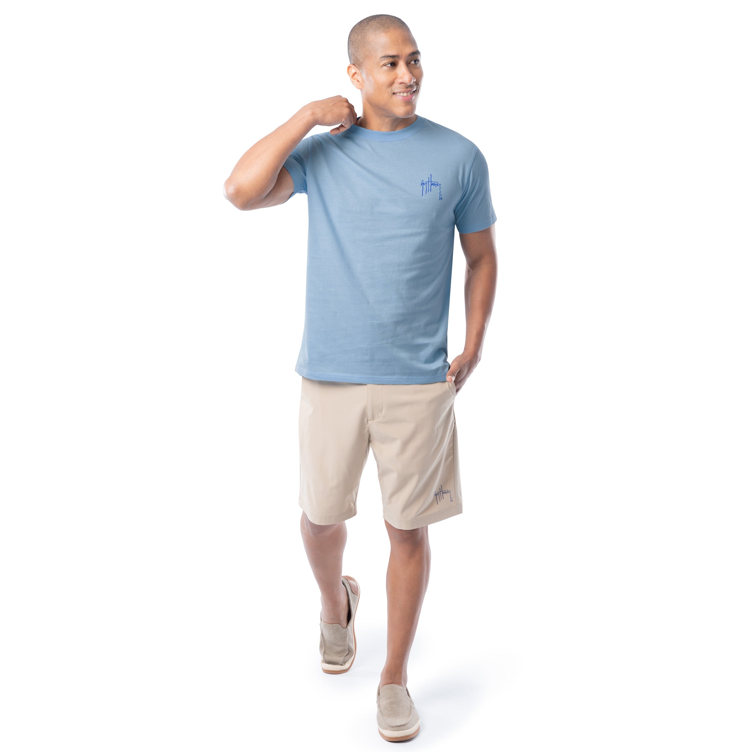 Man wearing a light blue t-shirt and beige shorts on a white background