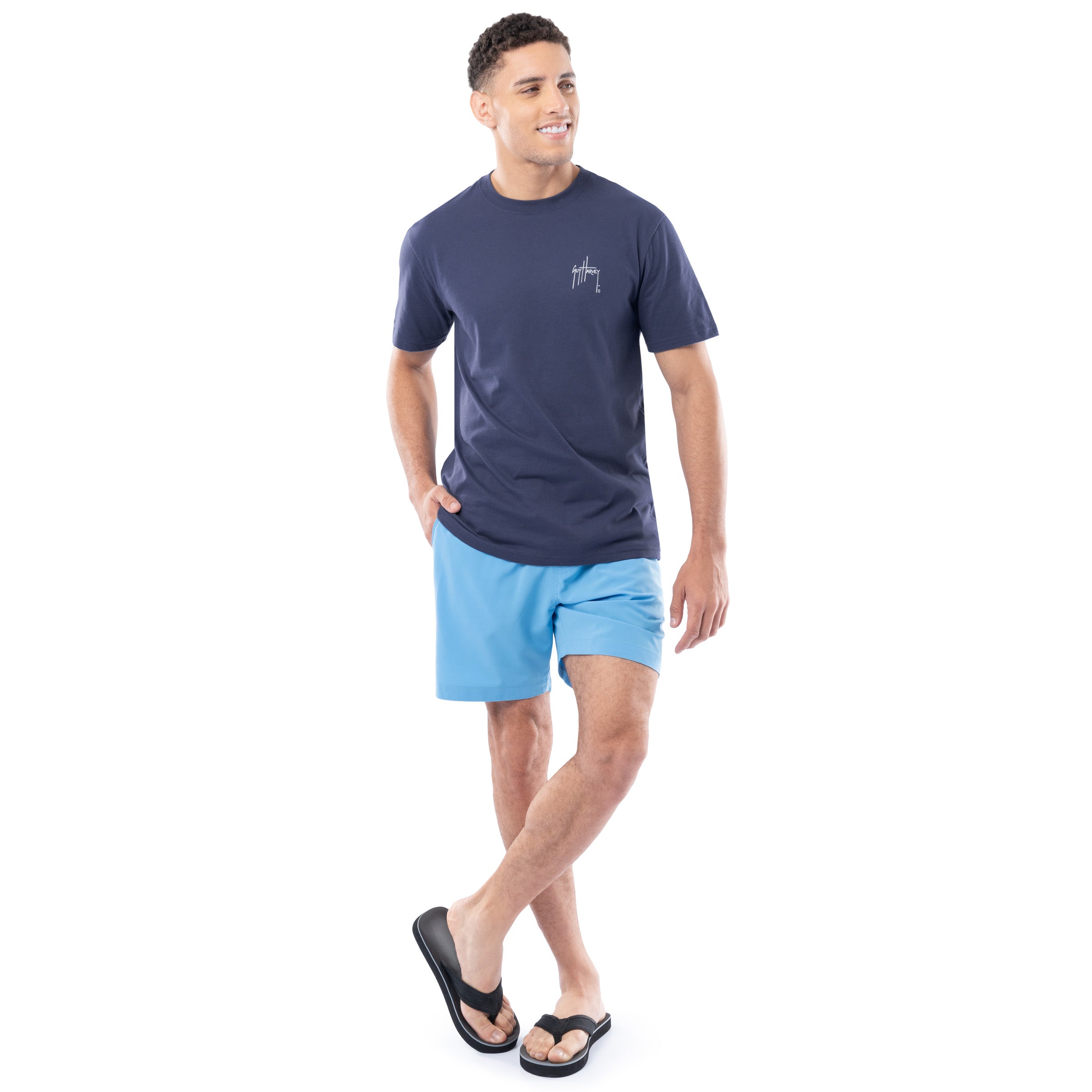 Man wearing a navy t-shirt and light blue shorts on a white background