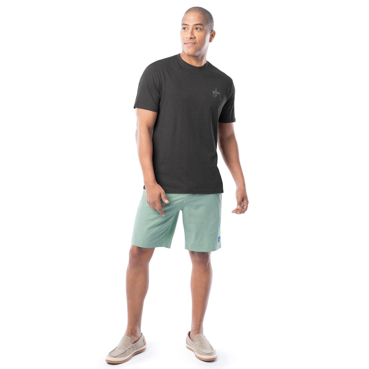 Man wearing a black t-shirt and light green shorts on a white background