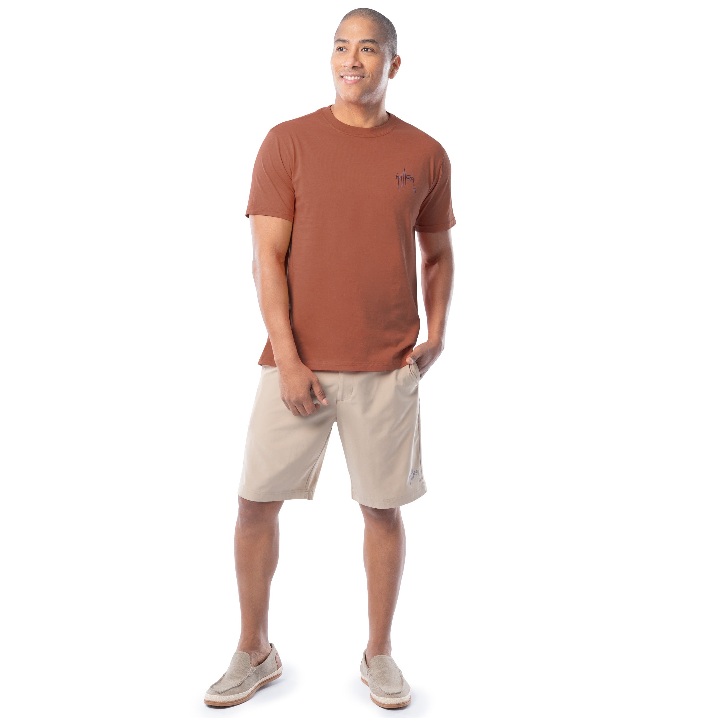 Man wearing a orange t-shirt and beige shorts on a white background