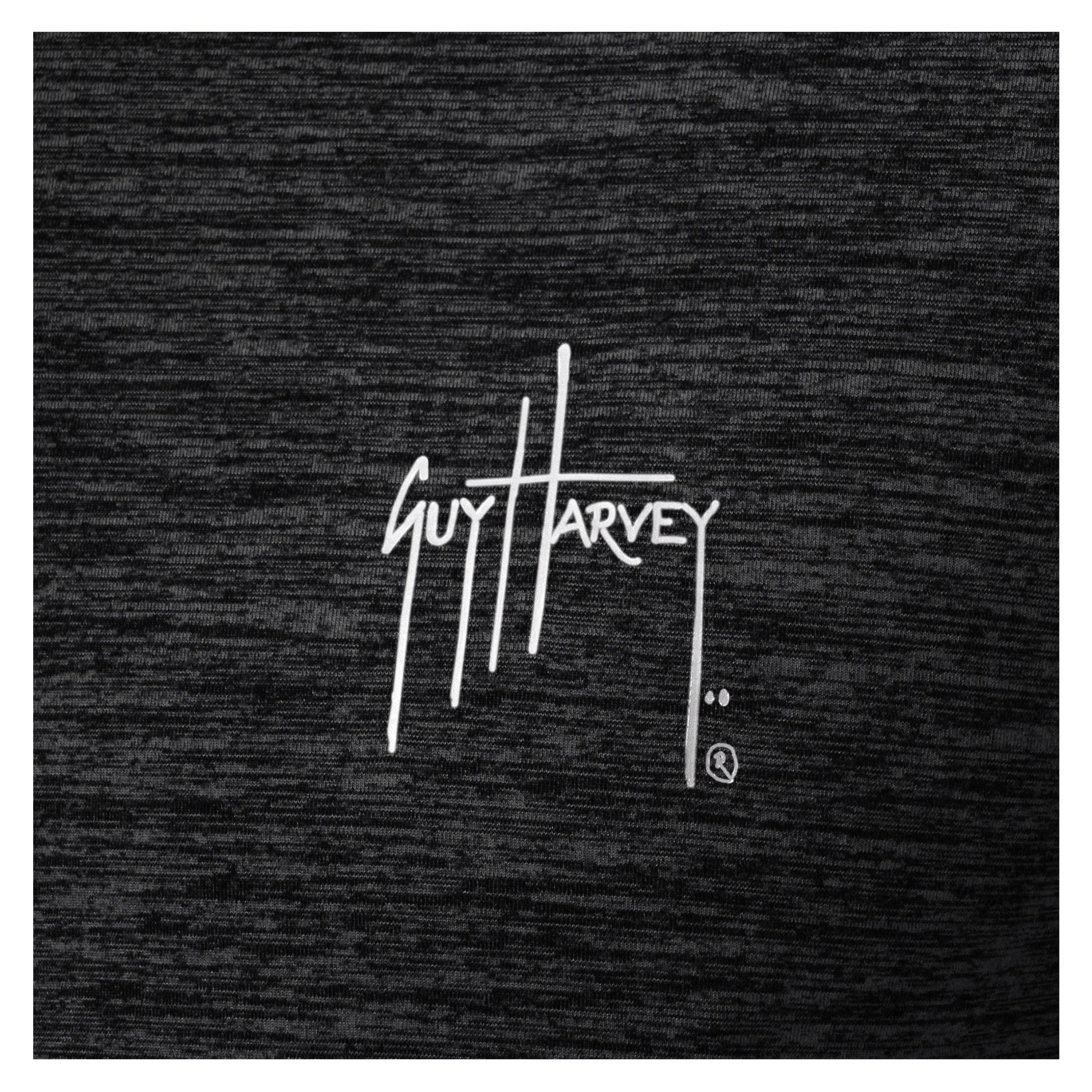 Close-up of white Guy Harvey logo printed on black brushed fleece fabric