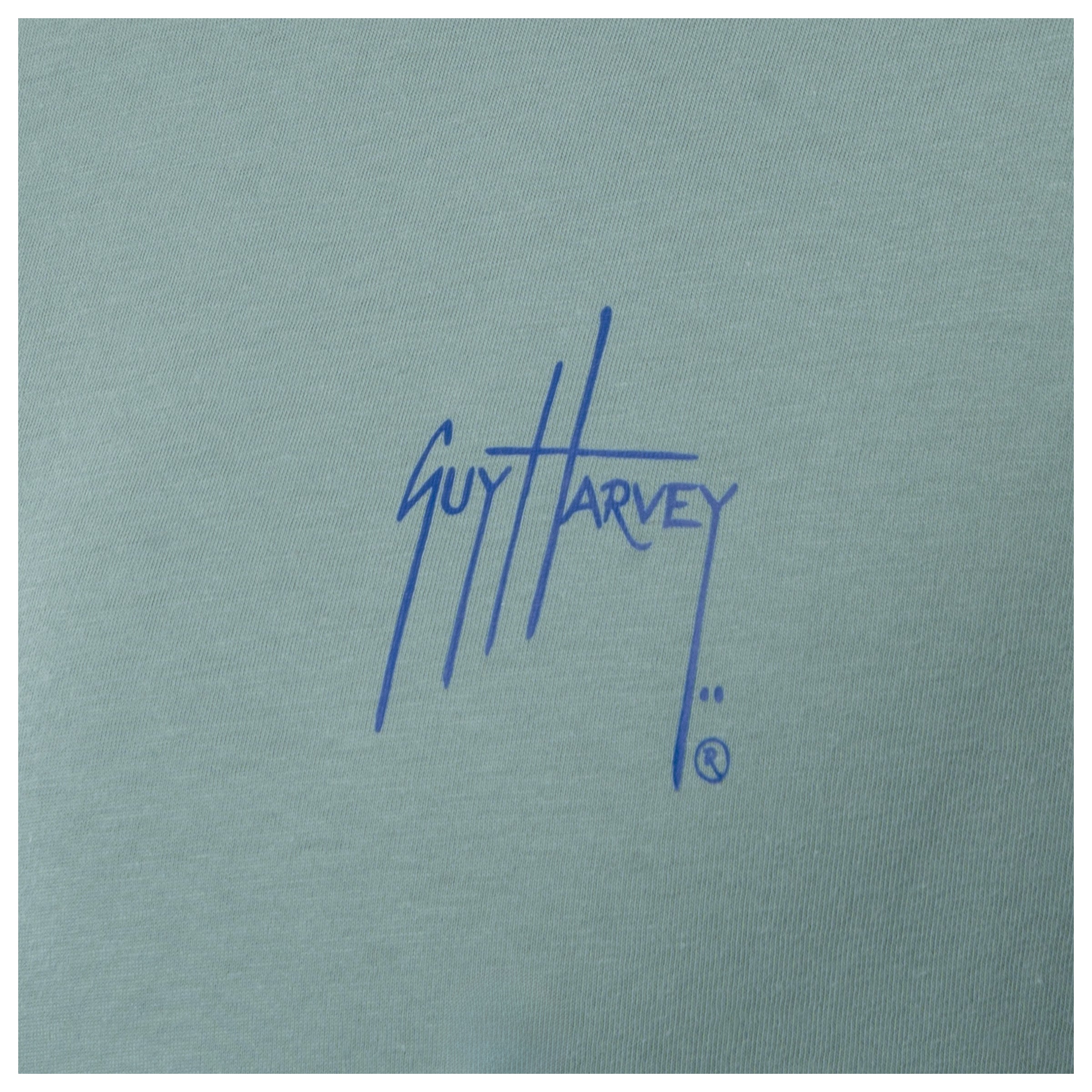 Close-up of blue Guy Harvey chest logo on men’s green freshwater fishing T-shirt