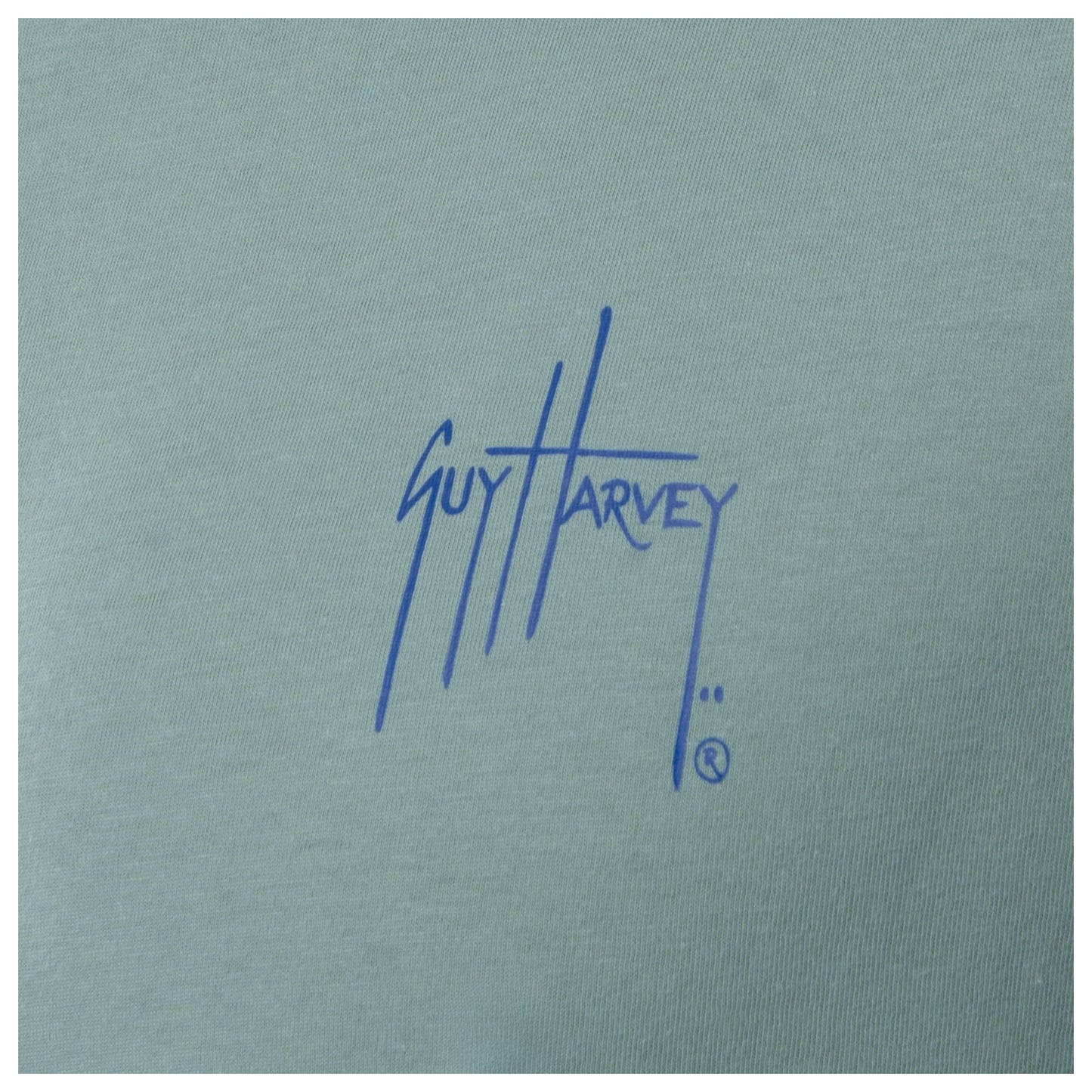 Close-up of blue Guy Harvey chest logo on men’s green freshwater fishing T-shirt