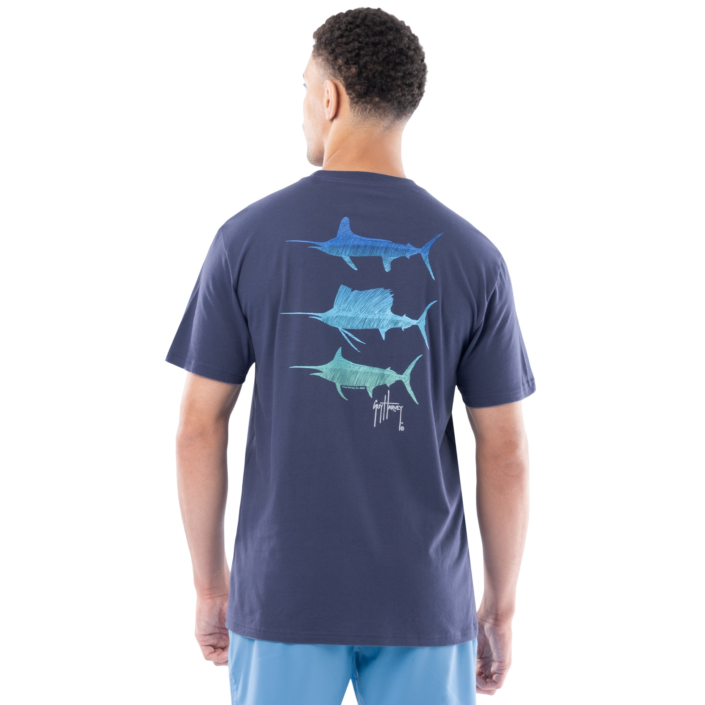 Man wearing a navy blue t-shirt with Marlin and sailfish graphics on the back, standing against a white background.