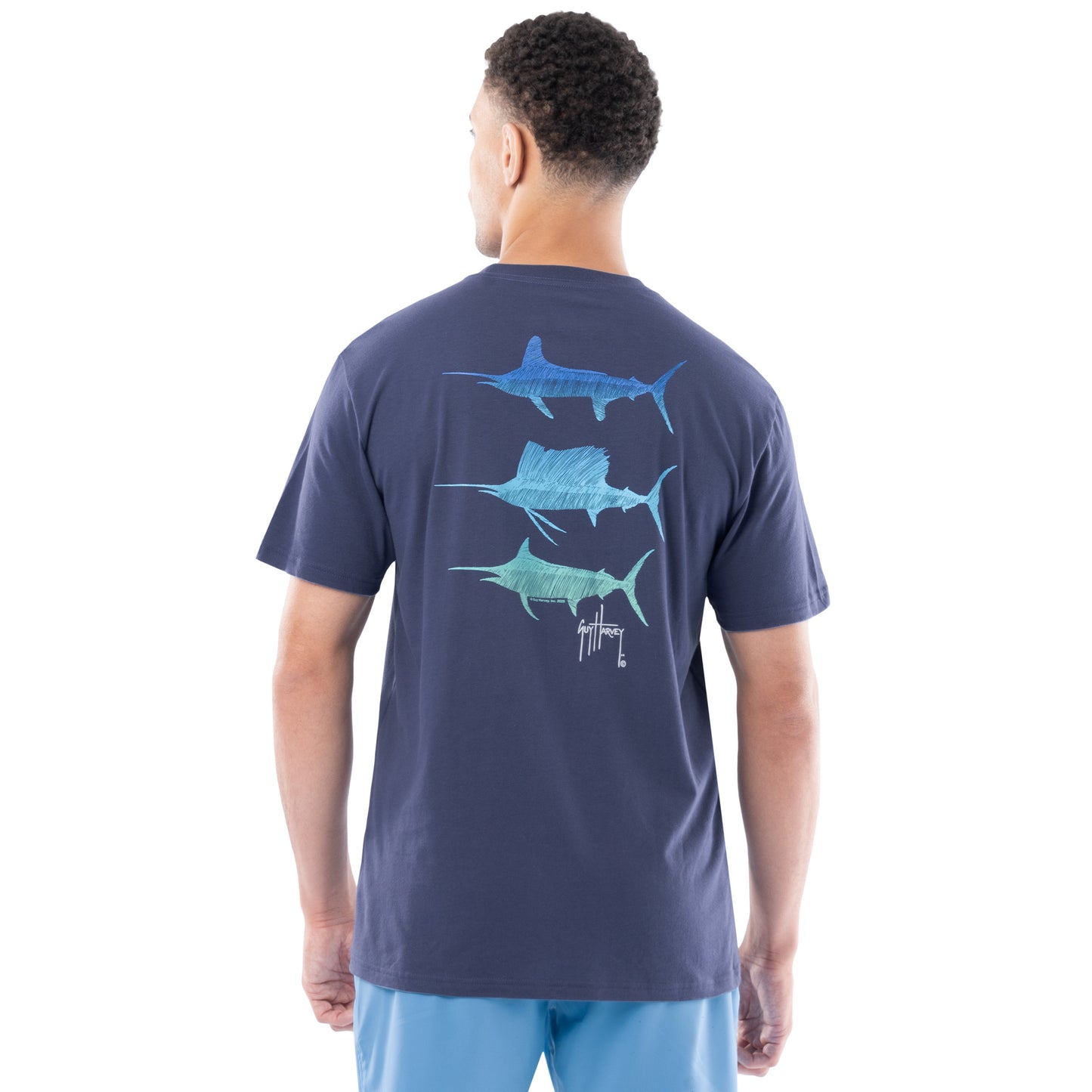 Man wearing a navy blue t-shirt with Marlin and sailfish graphics on the back, standing against a white background.