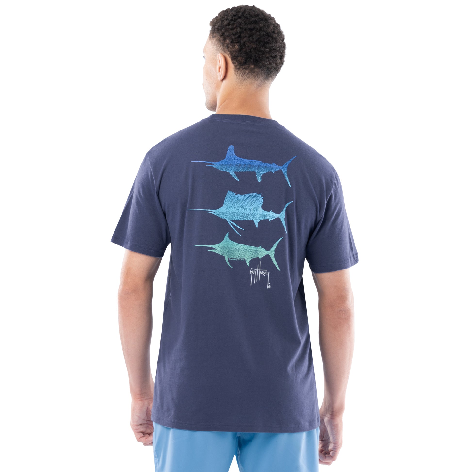 Man wearing a navy blue t-shirt with Marlin and sailfish graphics on the back, standing against a white background.