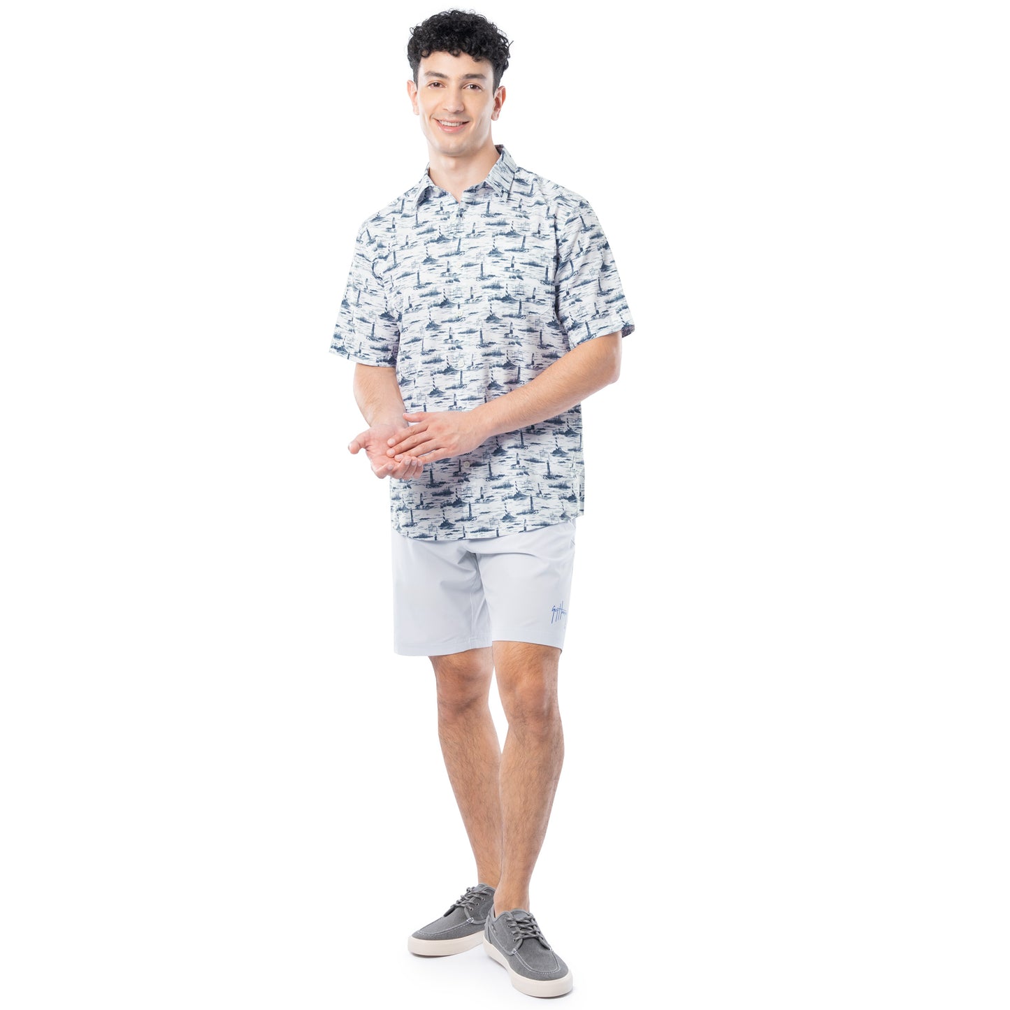 Man wearing a patterned shirt and light shorts on a white background