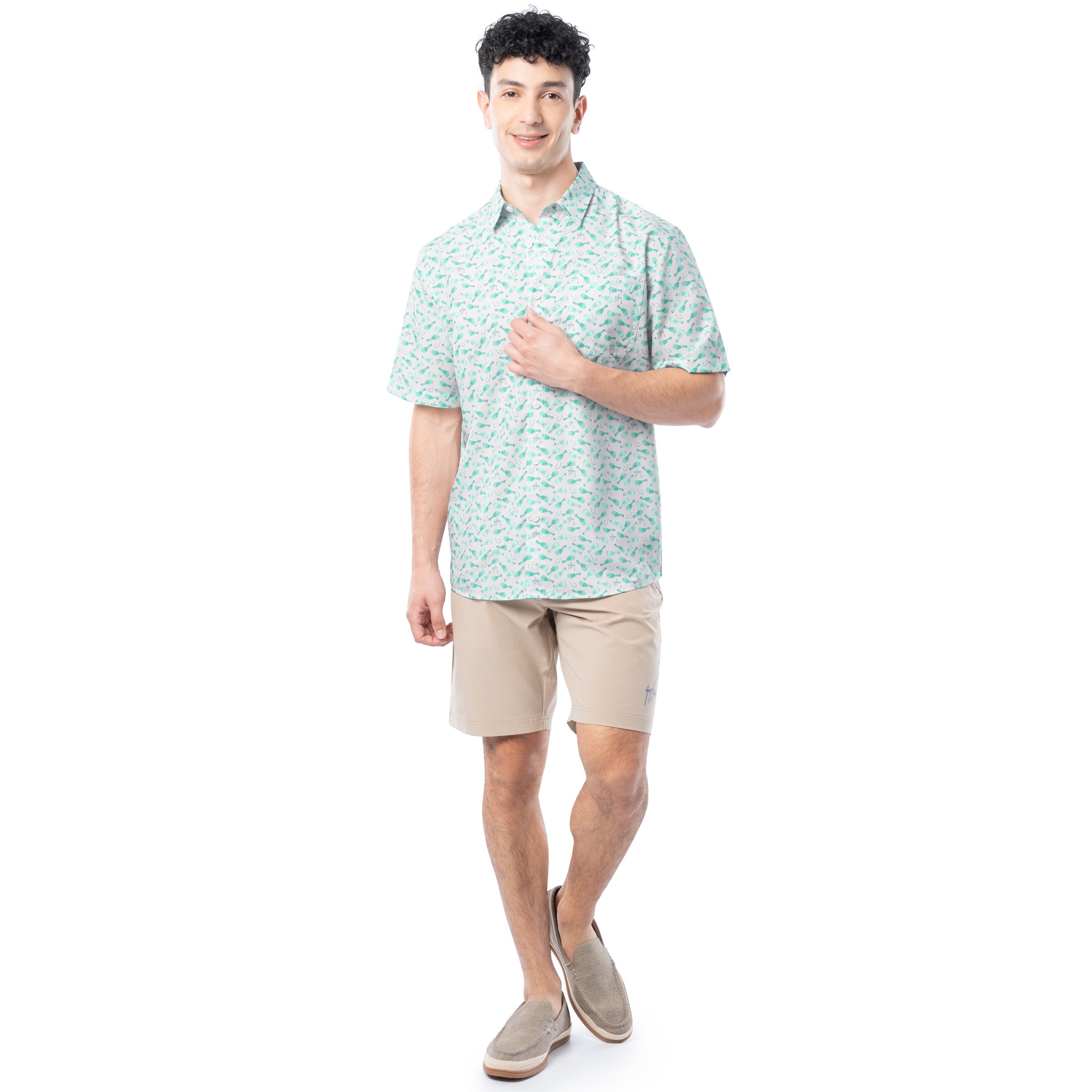 Man wearing a light green patterned shirt and beige shorts on a white background