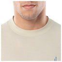 Close-up of a person wearing a beige shirt with a plain background