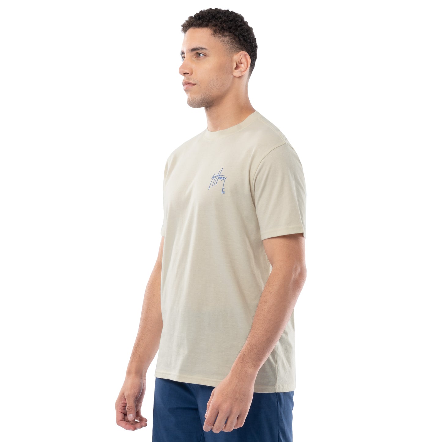 Man wearing a beige t-shirt with a small logo on a white background