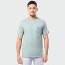 A man wearing a light green Guy Harvey t-shirt with a left chest pocket