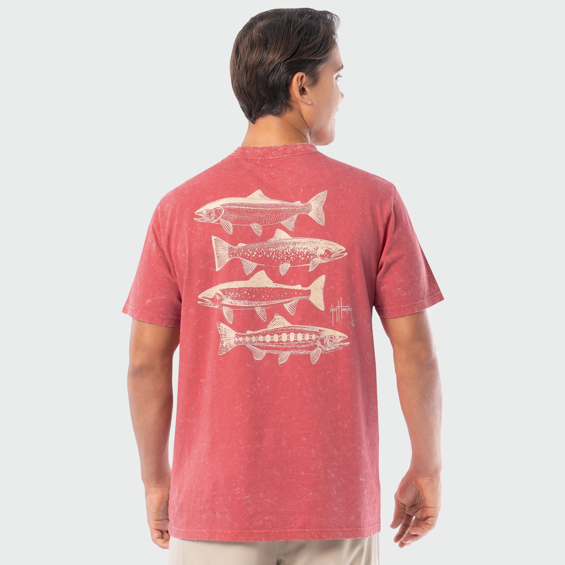 Person wearing a red washed t-shirt with white trout fish illustrations on the back against a white background