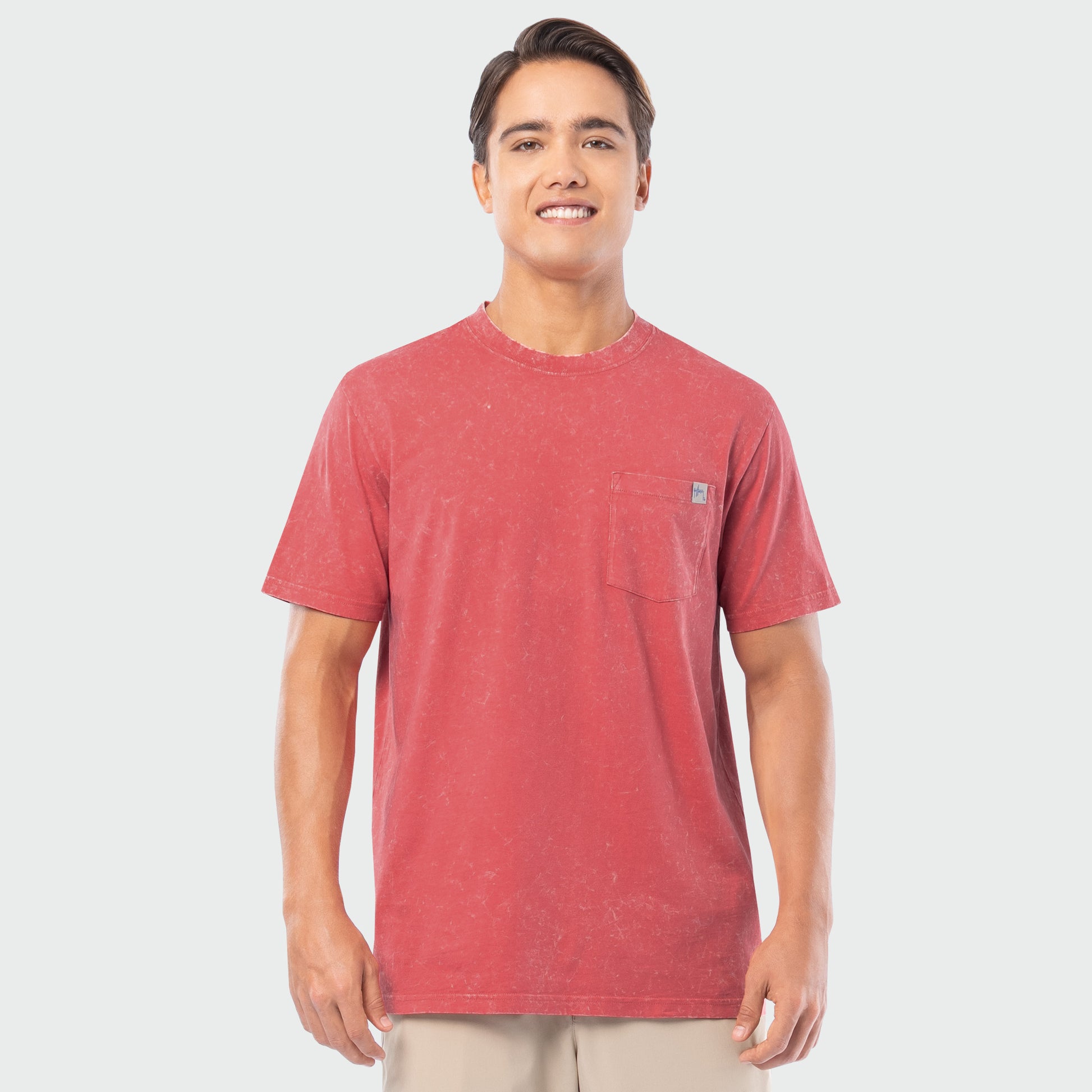 Man wearing a red washed t-shirt with a small logo on a white background