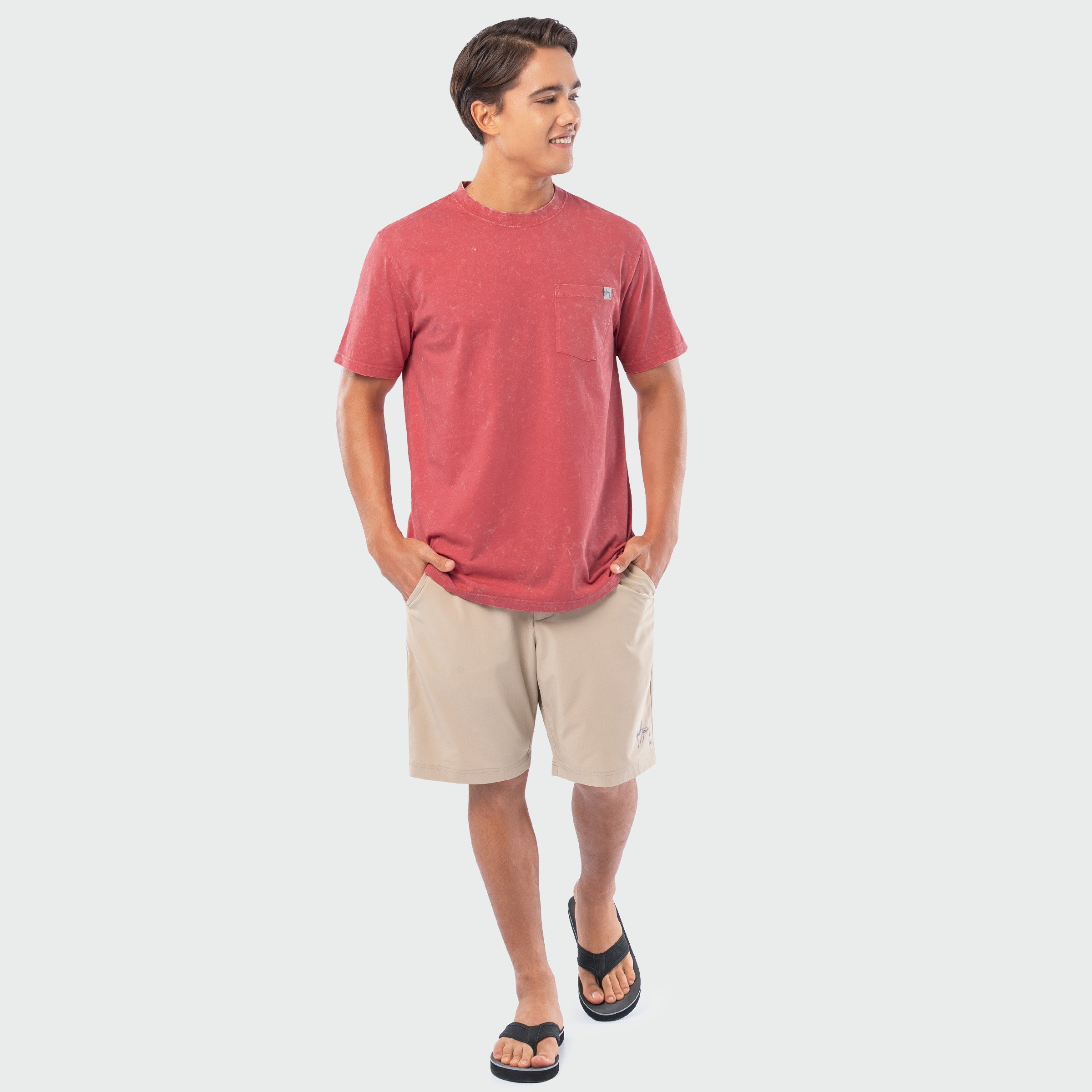 Man wearing a red t-shirt and beige shorts on a white background