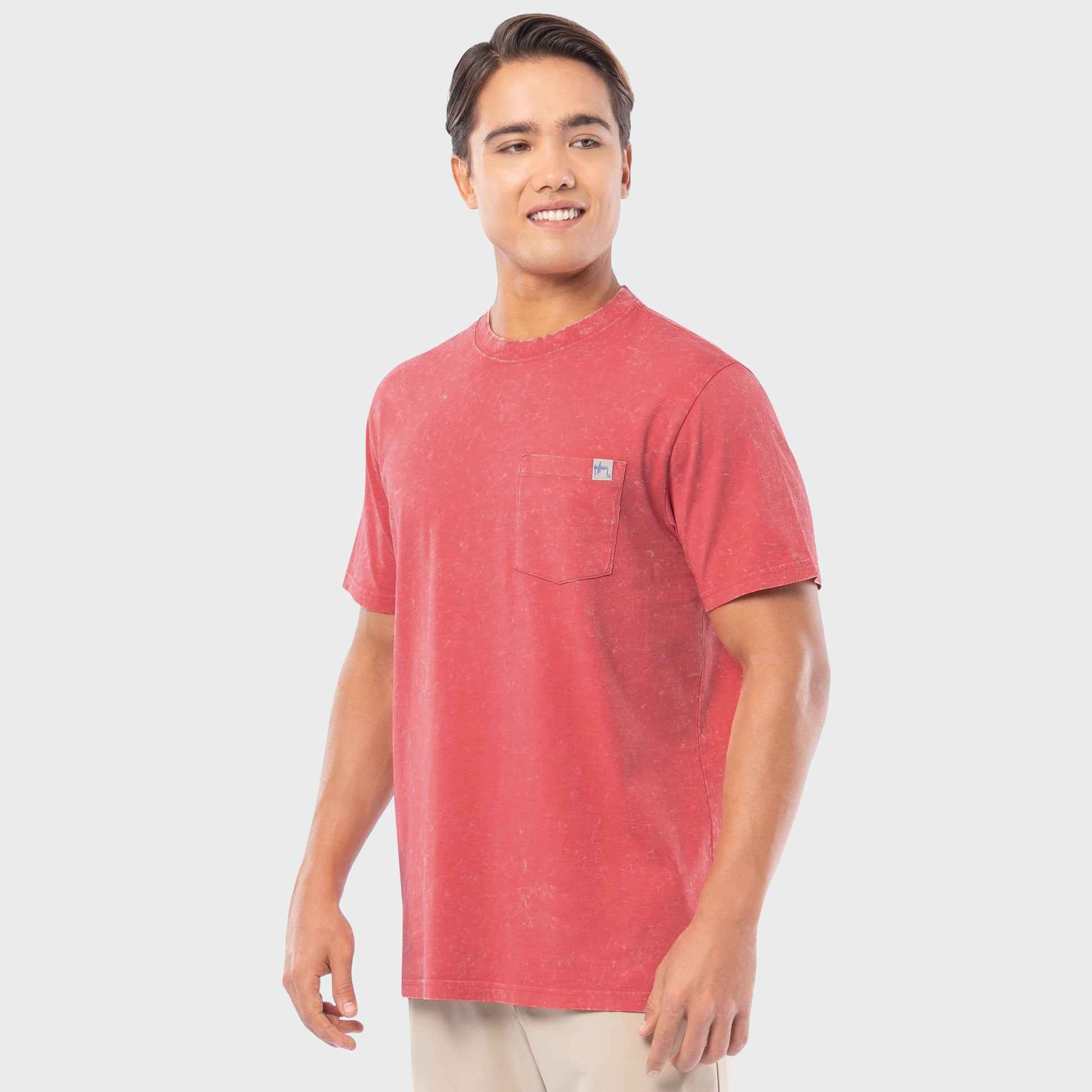 Man wearing a red washed t-shirt with a logo on a white background
