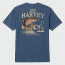 Flat lay image of a blue Guy Harvey t-shirt with a graphic of a trout fish and mountains on the back.