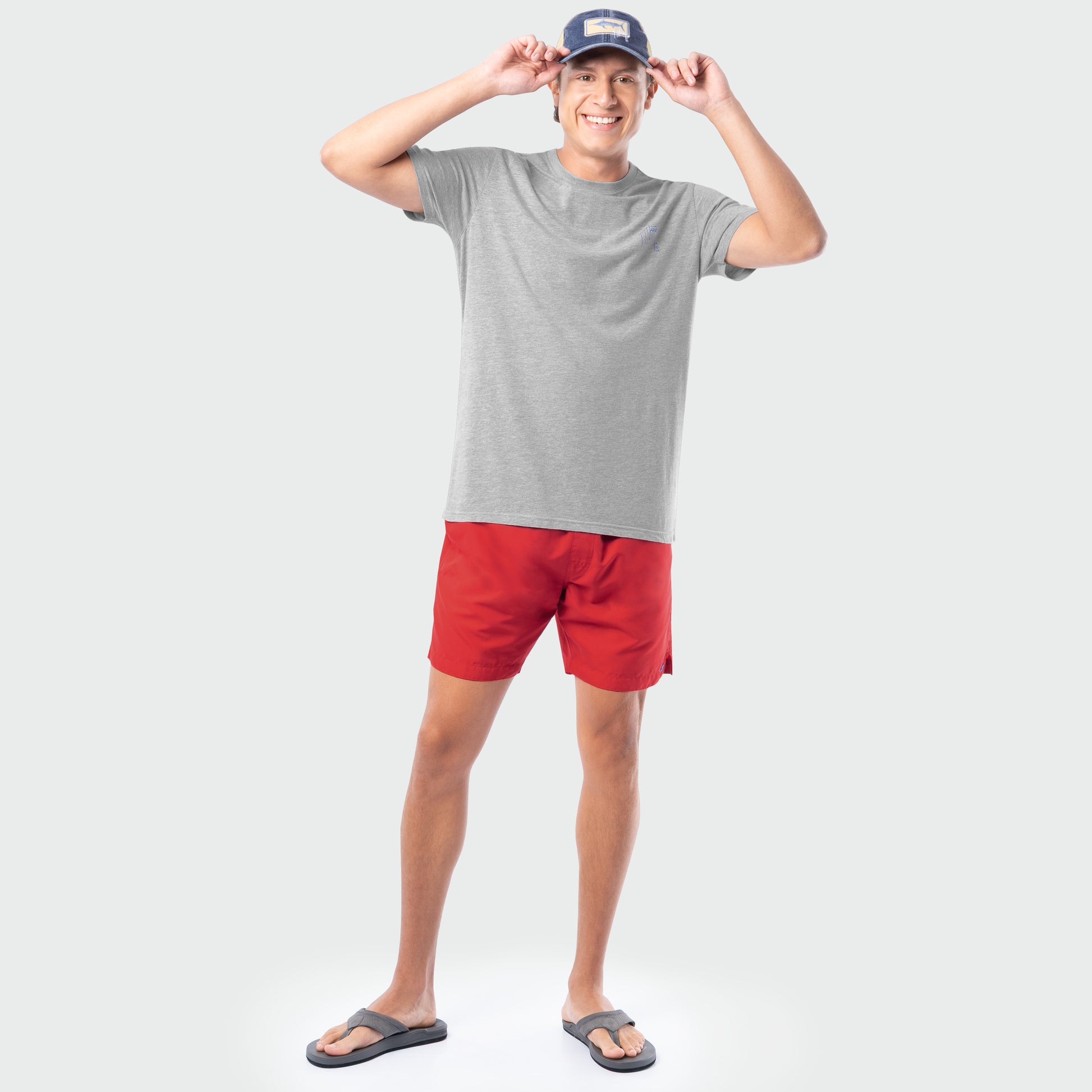 Man wearing a gray t-shirt, red shorts, and a cap on a white background