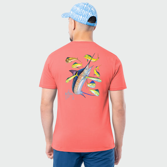 Man wearing a coral t-shirt with marlin and mahi fish design on the back, standing against a light gray background.
