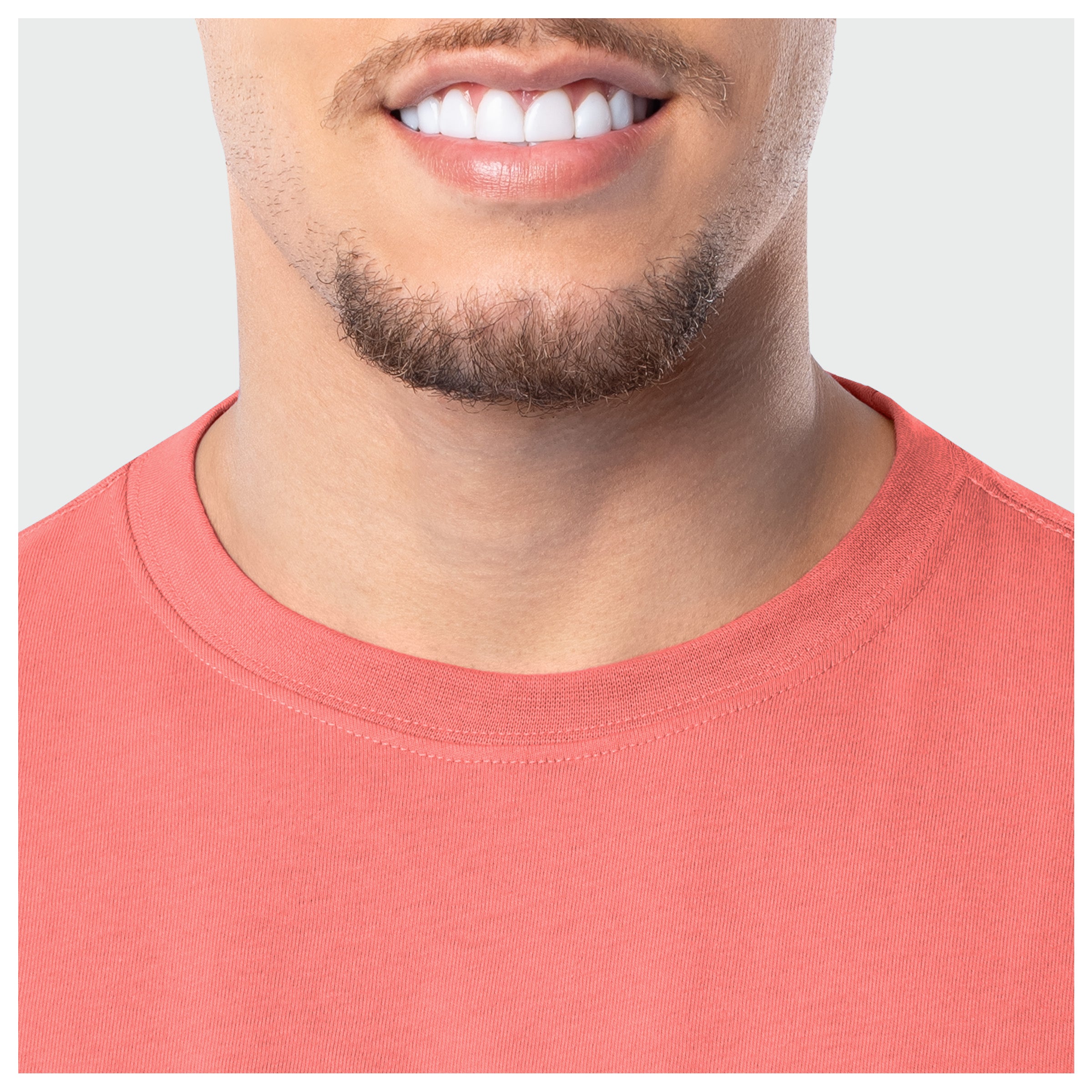 Close-up of a person wearing a coral t-shirt with a plain background