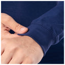 Close-up of a hand adjusting the cuff of a navy blue shirt.